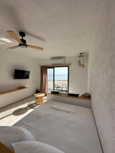 SPONGIA HOTEL AND SUITES في Myrties: غرفة بيضاء مع سرير ونافذة