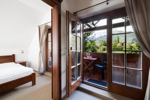 a bedroom with a bed and a balcony with a table at Vila GRAND in Smokovce