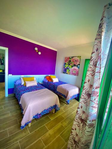 2 camas en una habitación con paredes moradas y moradas en ApKanariooo, en La Frontera