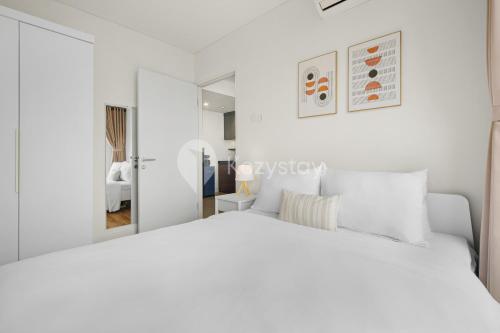 a white bedroom with a white bed and a mirror at Sarwa by Kozystay - Paskal in Bandung