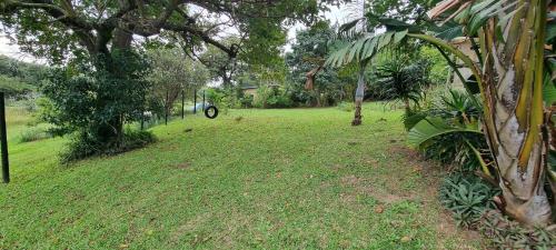 a grassy yard with a motorcycle in the distance at Secret Sithela in Port Edward