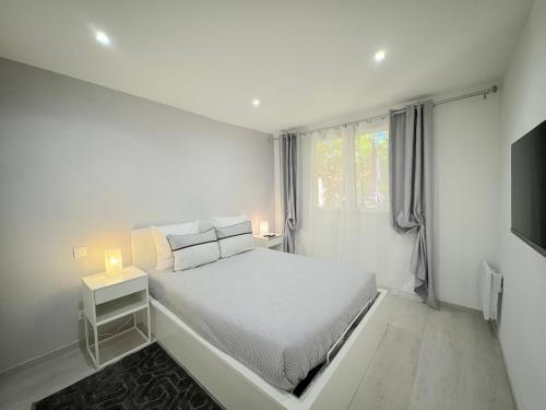 une chambre blanche avec un lit et une télévision dans l'établissement Beau 3P à 4 min des plages centre Juan Les Pins, à Antibes