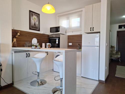 a kitchen with white cabinets and a counter with stools at White Sapphire in Karaburma
