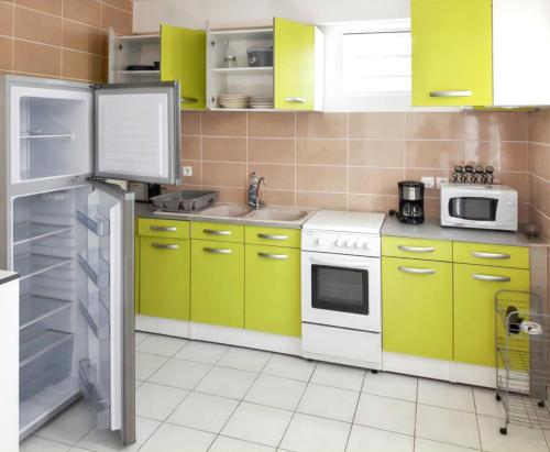 uma cozinha com armários amarelos e verdes e um frigorífico em Appartement de 2 chambres avec jardin clos et wifi a Ducos em Ducos