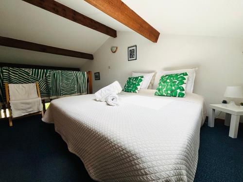 une chambre avec un grand lit blanc avec des oreillers verts dans l'établissement Chez mamie Paulette, Clim et Piscine, à 3 minutes à pied de la Plage, à Sanary-sur-Mer