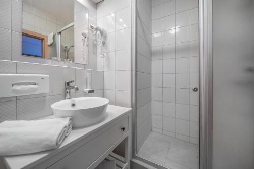 ein weißes Bad mit einem Waschbecken und einer Dusche in der Unterkunft Corvin Hotel Budapest Sissi Wing in Budapest