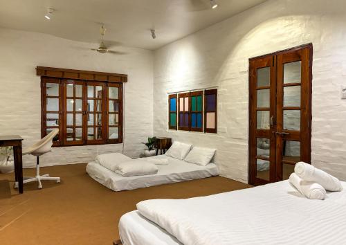 a bedroom with two beds and a table and a desk at ITH Luxury Cottage 'Hibiscus' in Varanasi