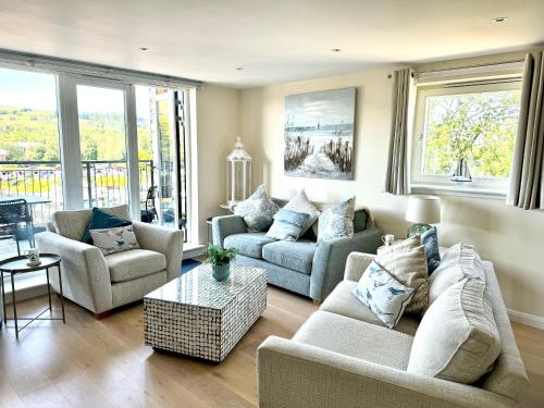 a living room with two couches and a table at Riverside View Penthouse in Balloch, Loch Lomond in Balloch