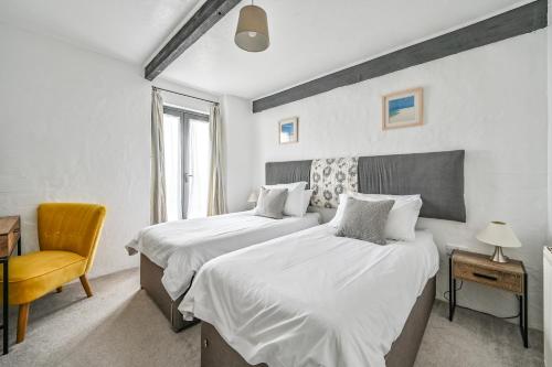 a bedroom with two beds and a chair and a desk at Goonwinnow Farm Cottages in Newquay