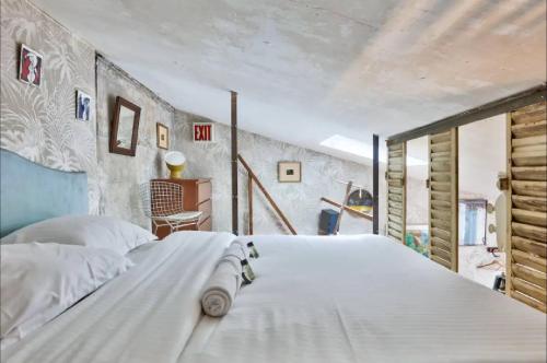 une chambre avec un grand lit blanc dans une pièce dans l'établissement Geranimus St Paul Coeur de paris, à Paris