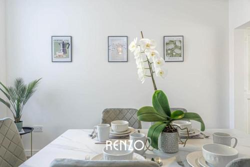 a dining room table with a vase with a white flower at Cosy and Lovely 3-bed Home in Lincoln by Renzo, Free Wi-Fi, Sleeps 8! in Lincolnshire