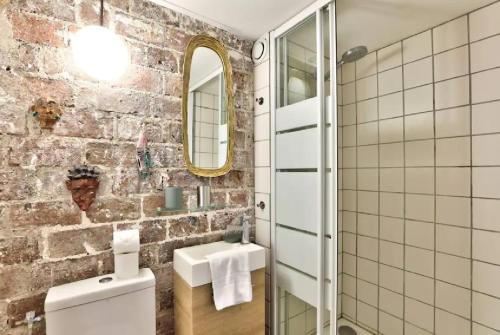 La salle de bains est pourvue de toilettes blanches et d'un mur en briques. dans l'établissement Geranimus St Paul Coeur de paris, à Paris