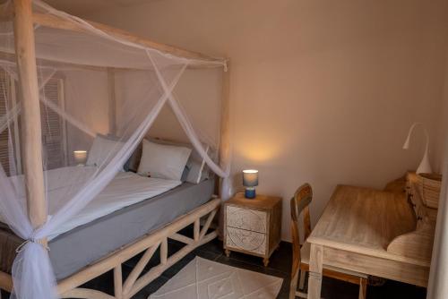 a bedroom with a canopy bed with a table and a chair at Finca Roberto by Don Robertos Finca Paraíso in Parque Holandes