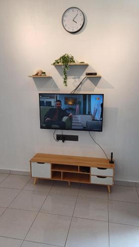 a flat screen tv on a wall with a clock at D' Tanjung Homestay-Orked in Pekan