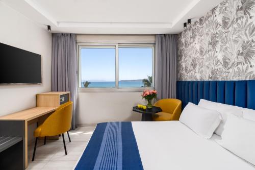 a hotel room with a bed and a desk and a window at Kenzi Solazur in Tangier