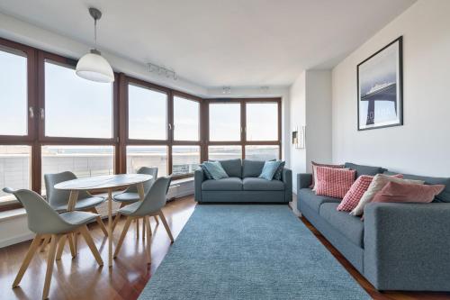 a living room with a couch and a table and chairs at Dom & House - Apartamenty Sea Towers in Gdynia