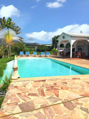 una piscina con sillas y una casa en Villa de 3 chambres avec vue sur la mer piscine privee et jardin clos a Le Carbet a 2 km de la plage en Le Carbet