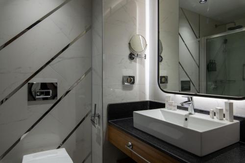 W łazience znajduje się biała umywalka i lustro. w obiekcie Ramada Resort by Wyndham Pamukkale Thermal w mieście Denizli