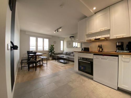 une cuisine avec des placards blancs et un salon avec une table dans l'établissement Grand appartement Standing reims centre Arena, à Reims