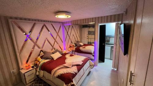 キトにあるGold House Oroの紫色の照明のある部屋にベッドが2つある