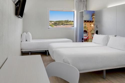 biały pokój z 2 łóżkami i kanapą w obiekcie B&B HOTEL Barcelona Granollers w mieście Les Franqueses del Vallès