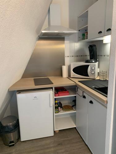 Elle comprend une petite cuisine avec des placards blancs et un réfrigérateur blanc. dans l'établissement Studio Pied télécabine Pas de l'Ours 4 Personnes, à Cauterets