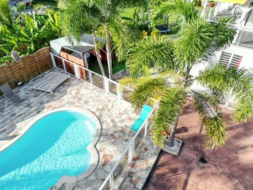 einen Blick über einen Pool mit Palmen in der Unterkunft Appartement d'une chambre avec piscine partagee jardin clos et wifi a Le Gosier in Le Gosier