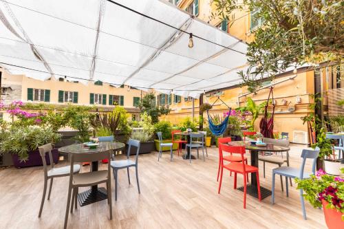 eine Terrasse mit Tischen, Stühlen und Pflanzen in der Unterkunft Ostello Bello Genova in Genua
