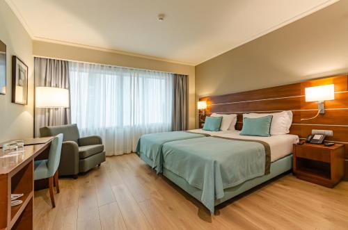 ein Hotelzimmer mit einem Bett und einem Stuhl in der Unterkunft TURIM Europa Hotel in Lissabon