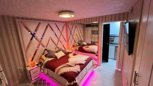 una camera da letto con due letti con illuminazione rosa di Gold House Oro a Quito