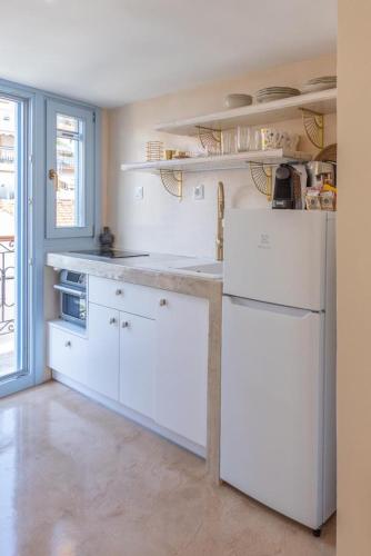 a kitchen with white cabinets and a white refrigerator at Manus Dei Exclusive Suites in Pythagoreio