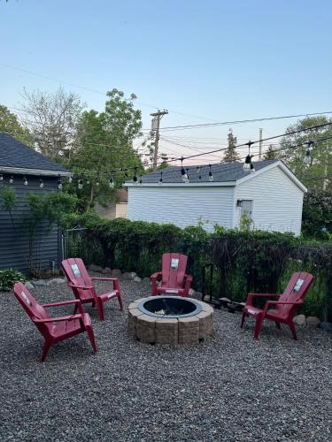 a group of red chairs sitting around a fire pit at Enchanting and comfy urban cottage with renovated rustic den by Como Park & MN State Fair in Saint Paul