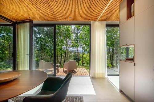 a dining room with a table and chairs and large windows at Villas Prendal Eco Living - Minho's Guest in Guimarães