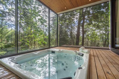 a jacuzzi tub on a deck with large windows at Villas Prendal Eco Living - Minho's Guest in Guimarães