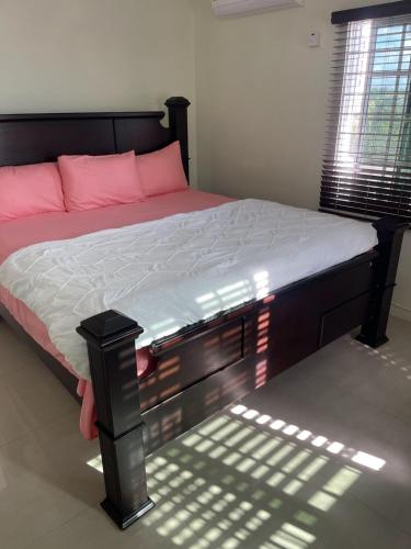 1 dormitorio con 1 cama con almohadas rosas en Three Palm Villa, en Montego Bay