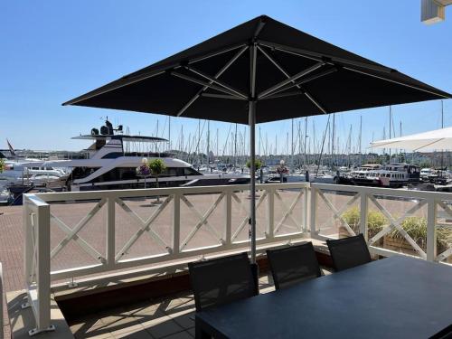 a table with an umbrella on a deck with a marina at Luxe appartement in de jachthaven van Port Zélande in Ouddorp