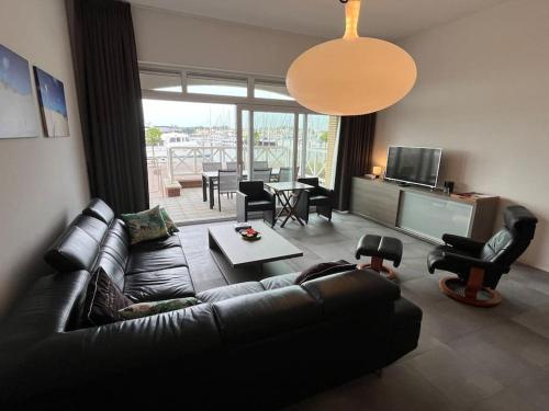 a living room with a black couch and a table at Luxe appartement in de jachthaven van Port Zélande in Ouddorp
