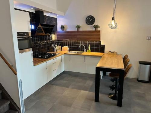 a kitchen with white cabinets and a wooden table at Luxe appartement in de jachthaven van Port Zélande in Ouddorp