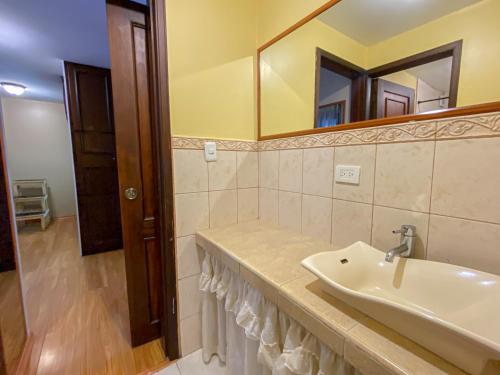 uma casa de banho com um lavatório e um espelho em Golden Rest Ecuador em Latacunga