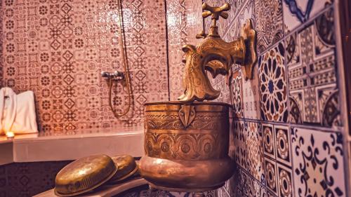 a bathroom with a gold vase on a table at Riad Dar Afram in Essaouira