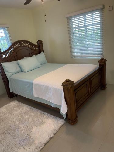 Schlafzimmer mit einem Bett mit weißer Bettwäsche und einem Fenster in der Unterkunft Three Palm Villa in Montego Bay