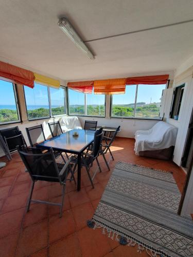 a dining room with a table and chairs and windows at Vila Vistazul in Pataias