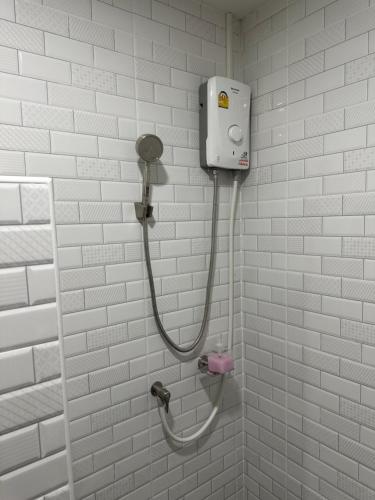 eine Dusche in einem weiß gefliesten Bad in der Unterkunft เดอะซันทูมูนโฮสเทล in Ban Hua Wiang Nua
