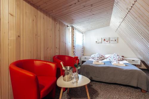 a bedroom with a bed and a red chair at Góralski Gościniec & SPA in Poronin