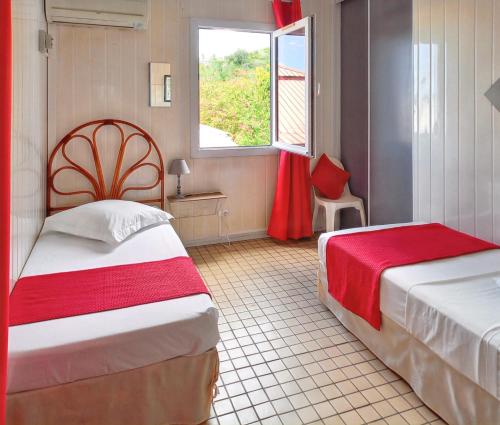 a hotel room with two beds and a window at Bungalow de 2 chambres a Bouillante a 150 m de la plage avec terrasse amenagee et wifi in Village