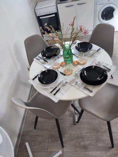 une table blanche avec des chaises, des assiettes et un vase de fleurs dans l'établissement Le petit château, à Pierrefonds