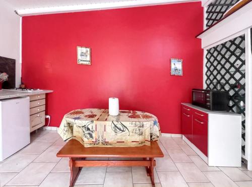 a kitchen with a red wall and a table with a candle at Appartement de 2 chambres avec jardin clos et wifi a Basse Terre in Basse-Terre