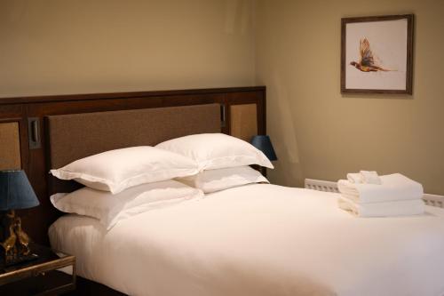 uma cama com lençóis brancos e almofadas num quarto em Galgorm em Ballymena