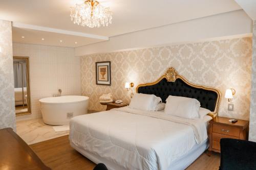 Hotel Daara في غرامادو: غرفة نوم بسرير كبير وحوض استحمام