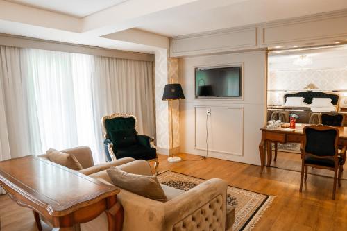 uma sala de estar com um sofá, uma mesa e uma cama em Hotel Daara em Gramado